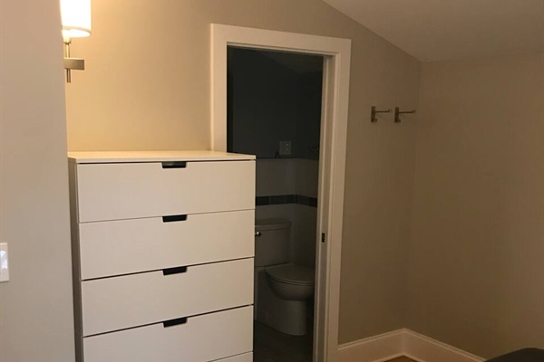 The bedroom space has a large drawer set for your clothing. The bathroom is behind the bedroom. It has a pocket door.