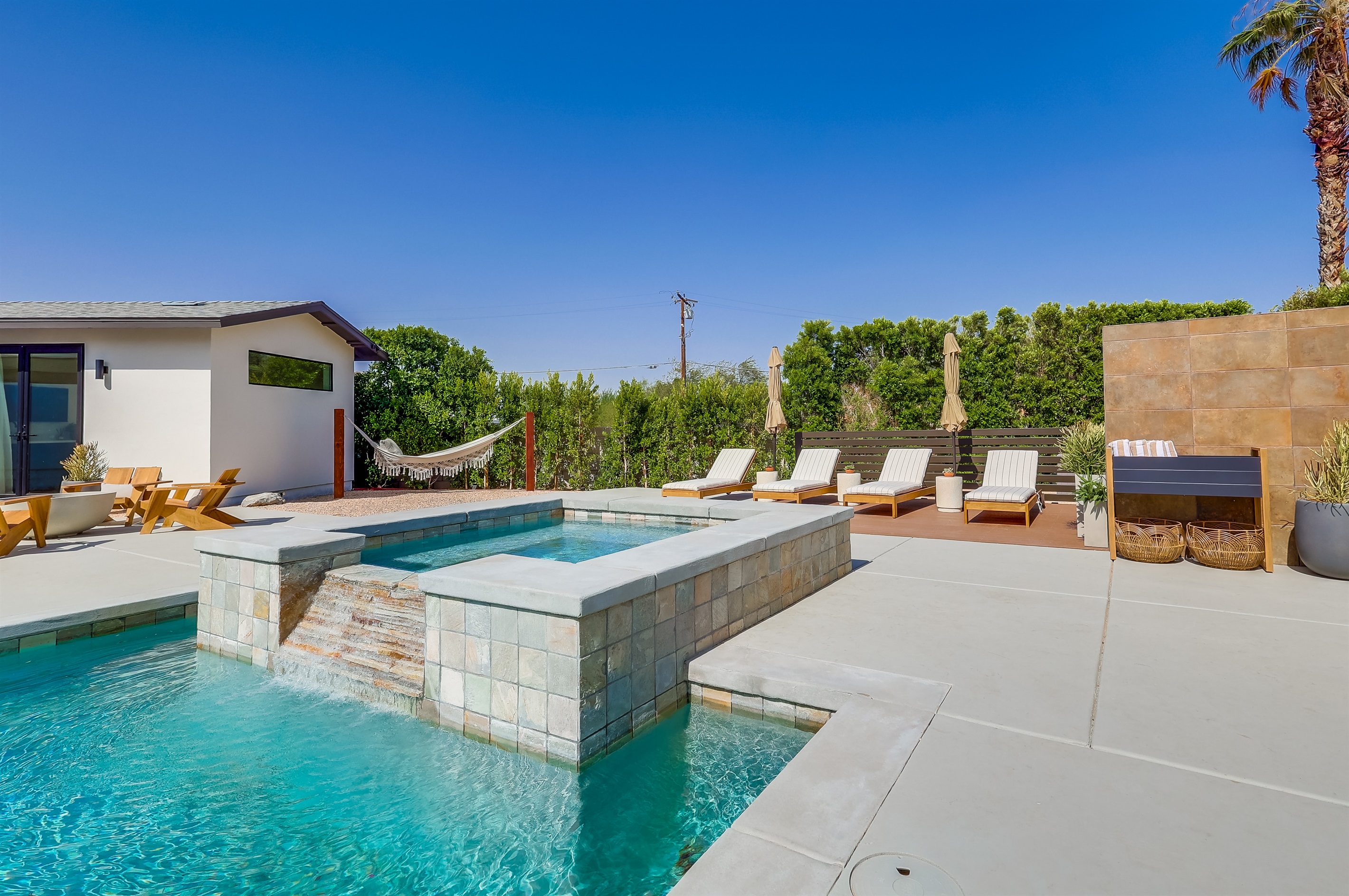 Outdoor space with several seating areas, pool chaise loungers
