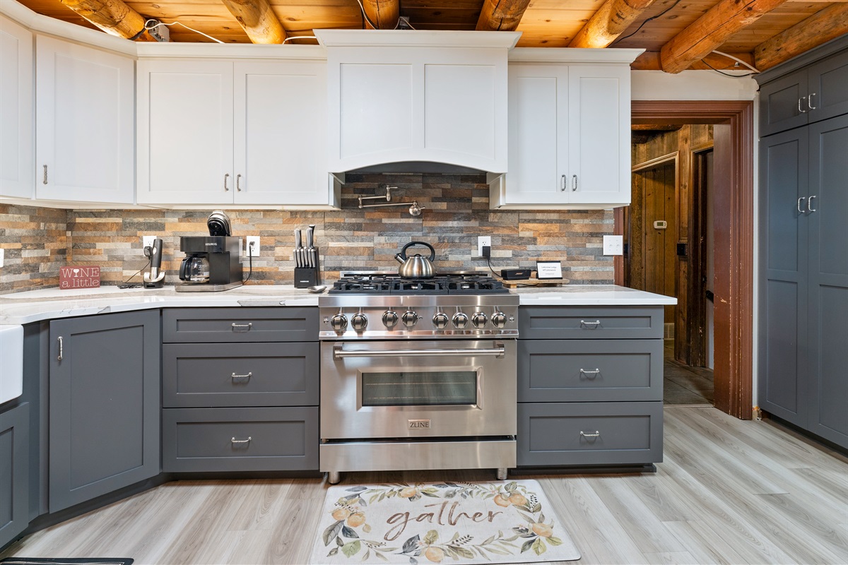 Elegant farmhouse sink, stone backsplash, and premium appliances add modern luxury to this classic log cabin kitchen.