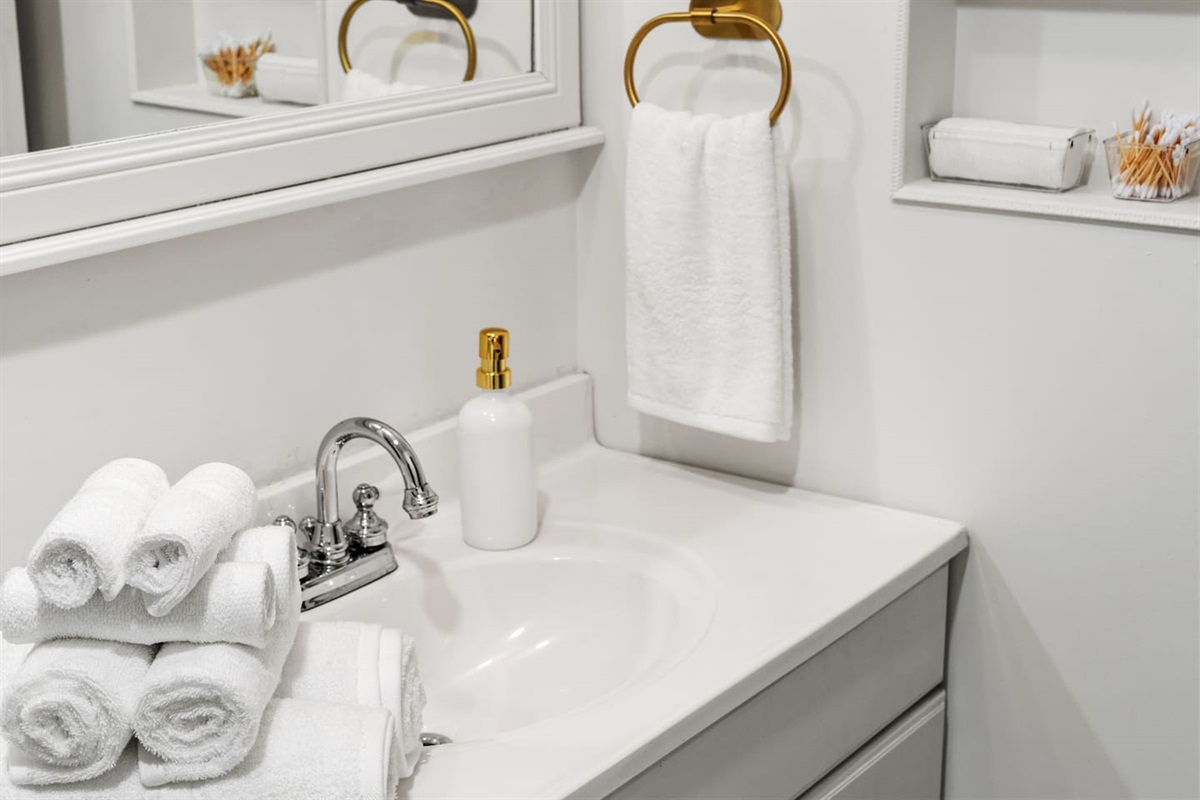 Sparkling clean vanity with fresh towels, gold accents, and thoughtful toiletries—your spa-like bathroom retreat starts here.