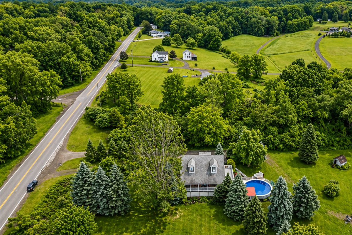 This picturesque property features a charming home, a refreshing pool, and lush greenery, offering a serene countryside retreat.