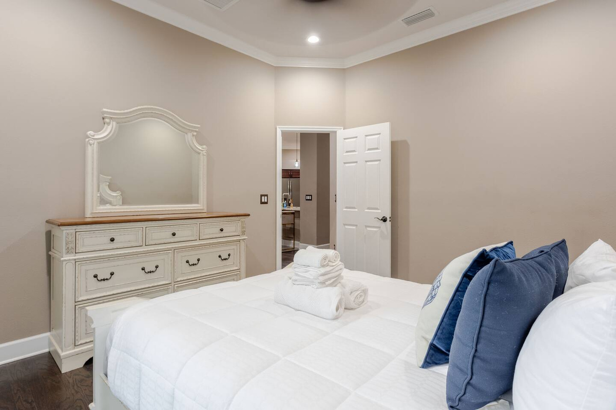 Elegant guest bedroom featuring a plush, inviting bed, sophisticated furnishings, and a spacious dresser for convenient storage—creating a refined, comfortable retreat for a restful stay.
