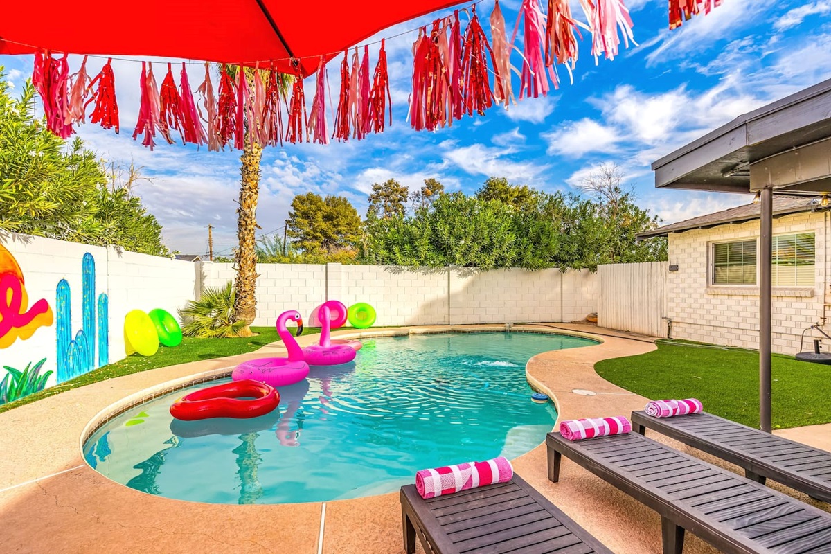 Soak up the Arizona sunshine on sleek loungers by the pool, shaded by a festive red umbrella and surrounded by vibrant greenery.

