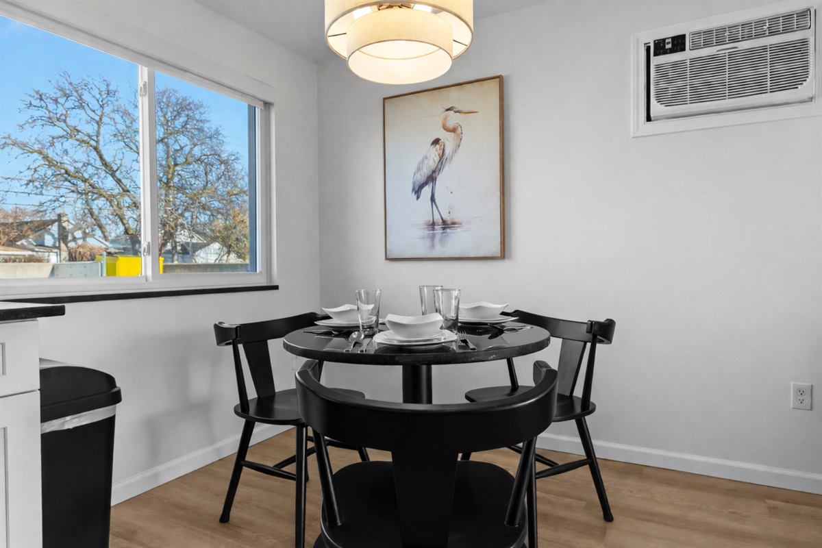 Modern dining area with stylish lighting, seating for four, and natural light—perfect for relaxed meals, morning coffee, or casual evenings together.