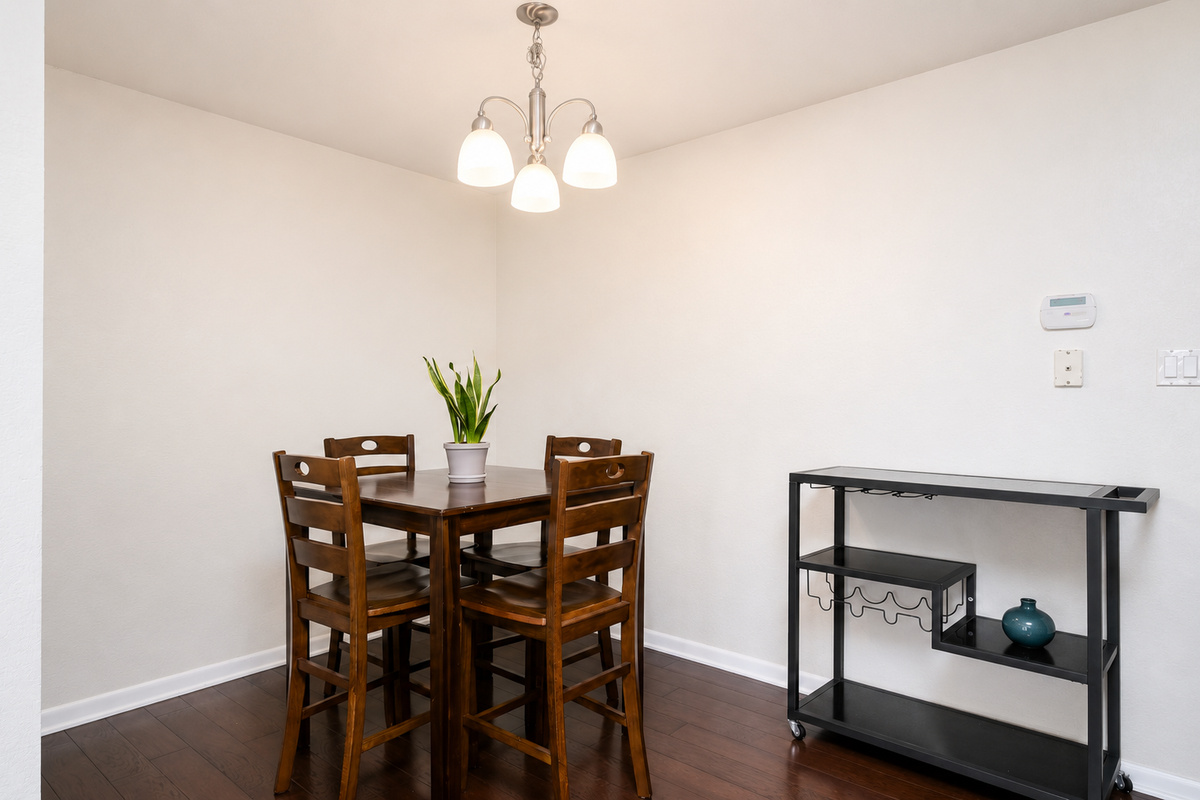 Simple dining setup with seating for four and a nearby storage cart for added convenience.