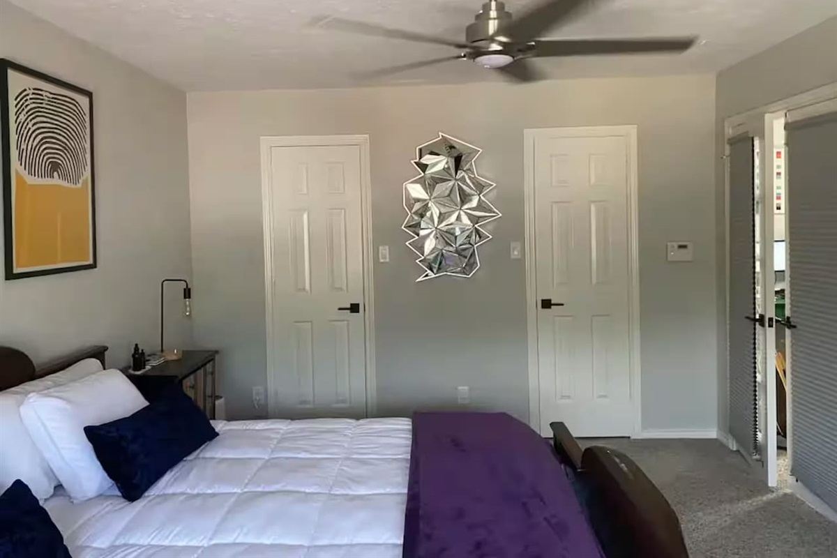 Spacious bedroom with king bed and vibrant wall art.
