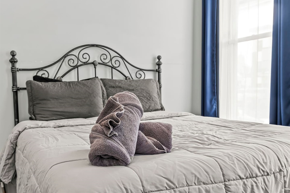 Close-up of the queen-size bed with plush pillows, fresh linens, and a welcoming hotel-style setup.