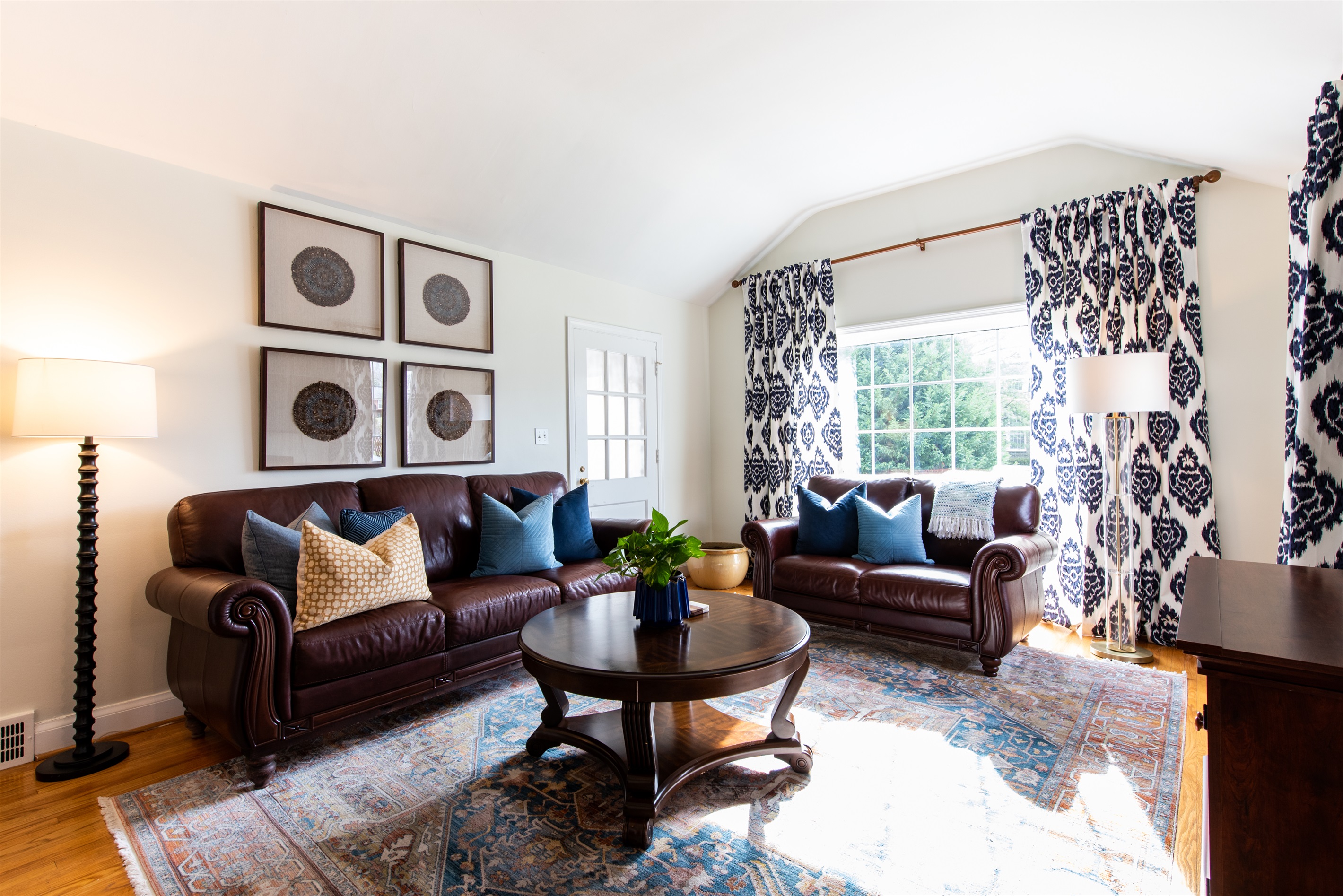 Relax in this stylish living room after the Bourbon Trail! Features leather sofas, a wooden coffee table, patterned curtains, and cozy lamps—perfect for unwinding with a drink. 