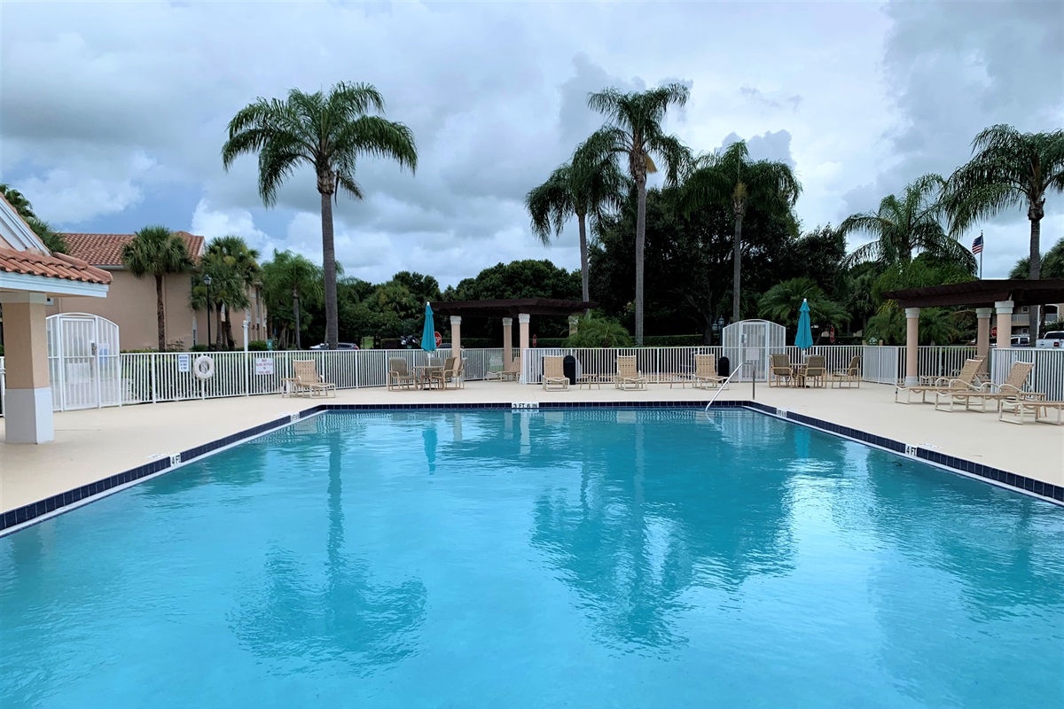 Spacious community pool surrounded by tropical landscaping, lounge chairs, and a peaceful Florida atmosphere.