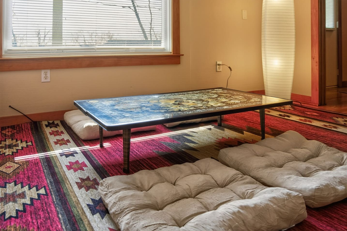 Relax in a Japanese-style living room with a low table, floor seating cushions, and warm, calming design—perfect for tea, conversation, or quiet moments, blending comfort and culture into a unique, peaceful retreat experience
