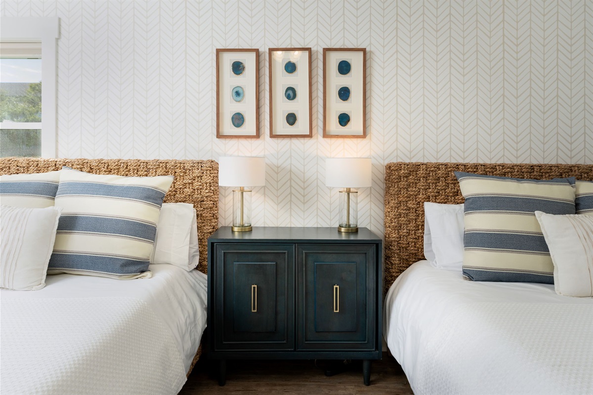 Thoughtfully designed guest suite featuring two queen beds, coastal textures, and a calm, inviting atmosphere.