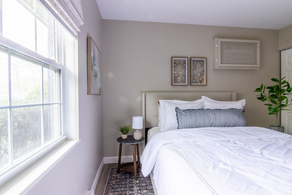 Natural light spills through the window, warming up the crisp white bedding and cozy textures.