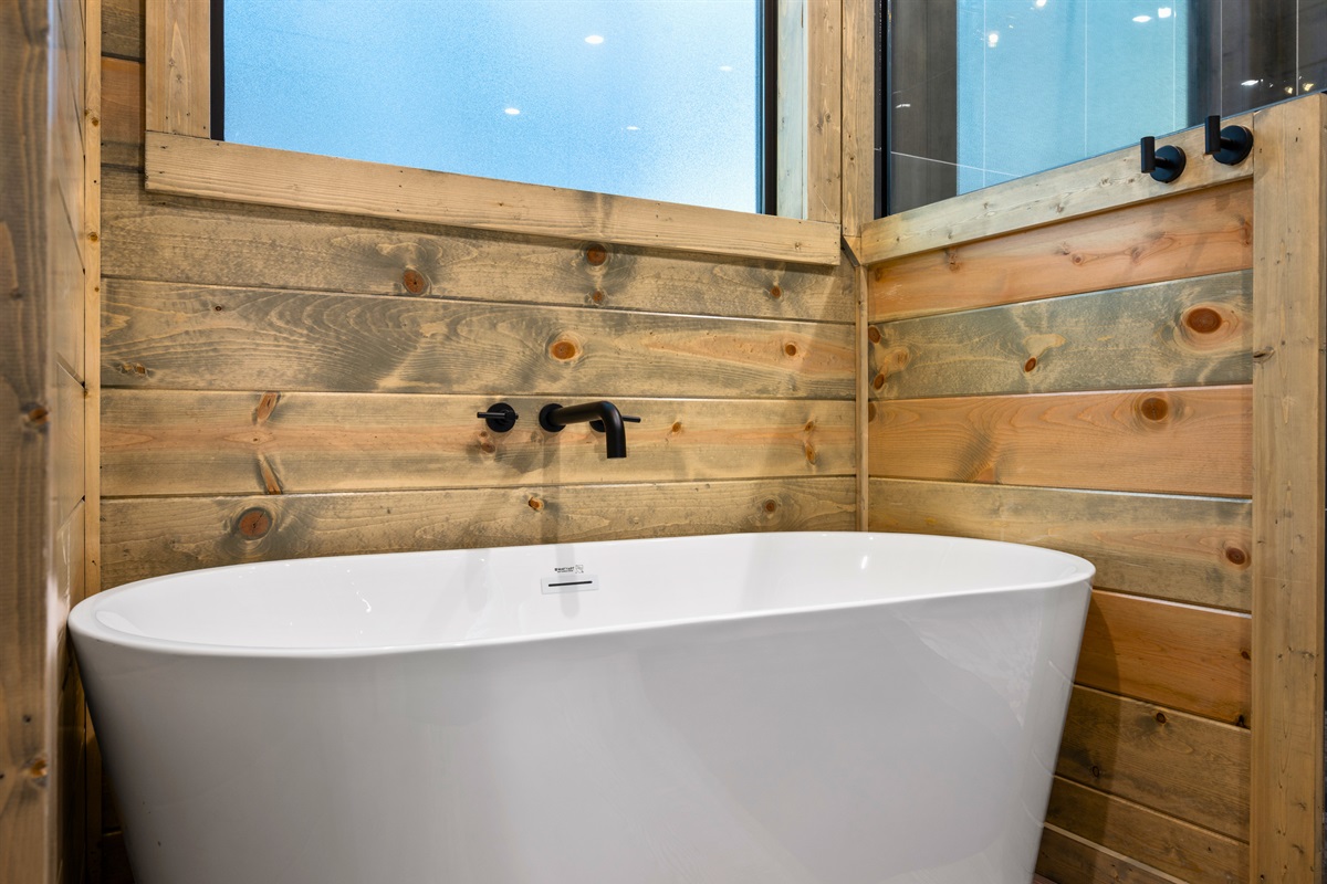 A freestanding soaking tub sits against warm wood accents, creating a peaceful space to relax and enjoy a long, quiet soak.