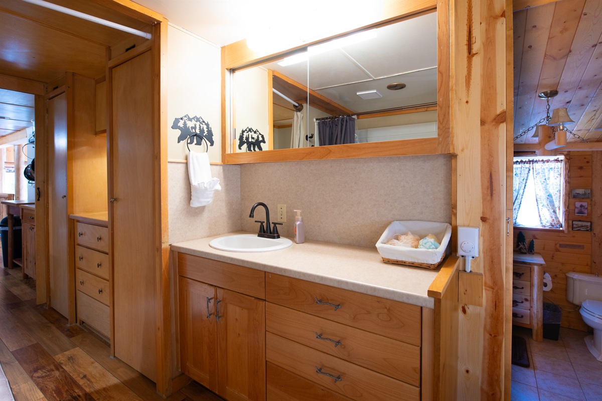 Vanity across from the tub/shower, with a two-step walkdown to Bedroom 2’s half bath, closed off by a pocket door.