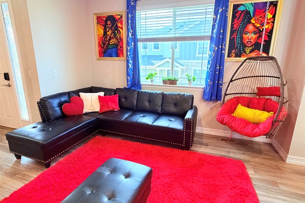 Cozy lounge nook featuring a sectional and hanging chair—great for reading or unwinding.