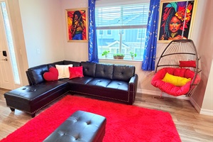 Cozy lounge nook featuring a sectional and hanging chair—great for reading or unwinding.