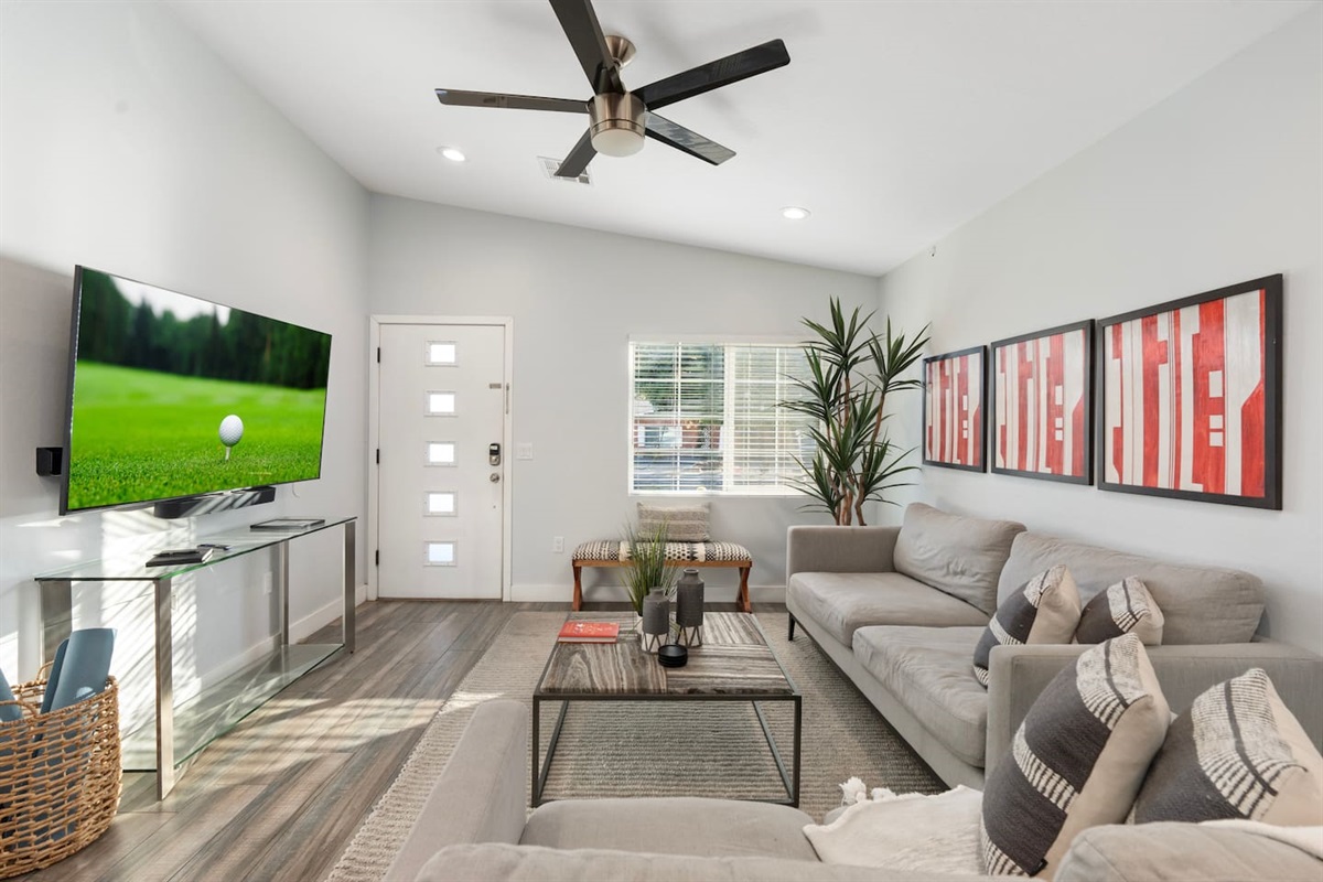 Spacious living room with soft gray sofas, chic wall art, and a stylish coffee table, perfect for relaxing or entertaining.