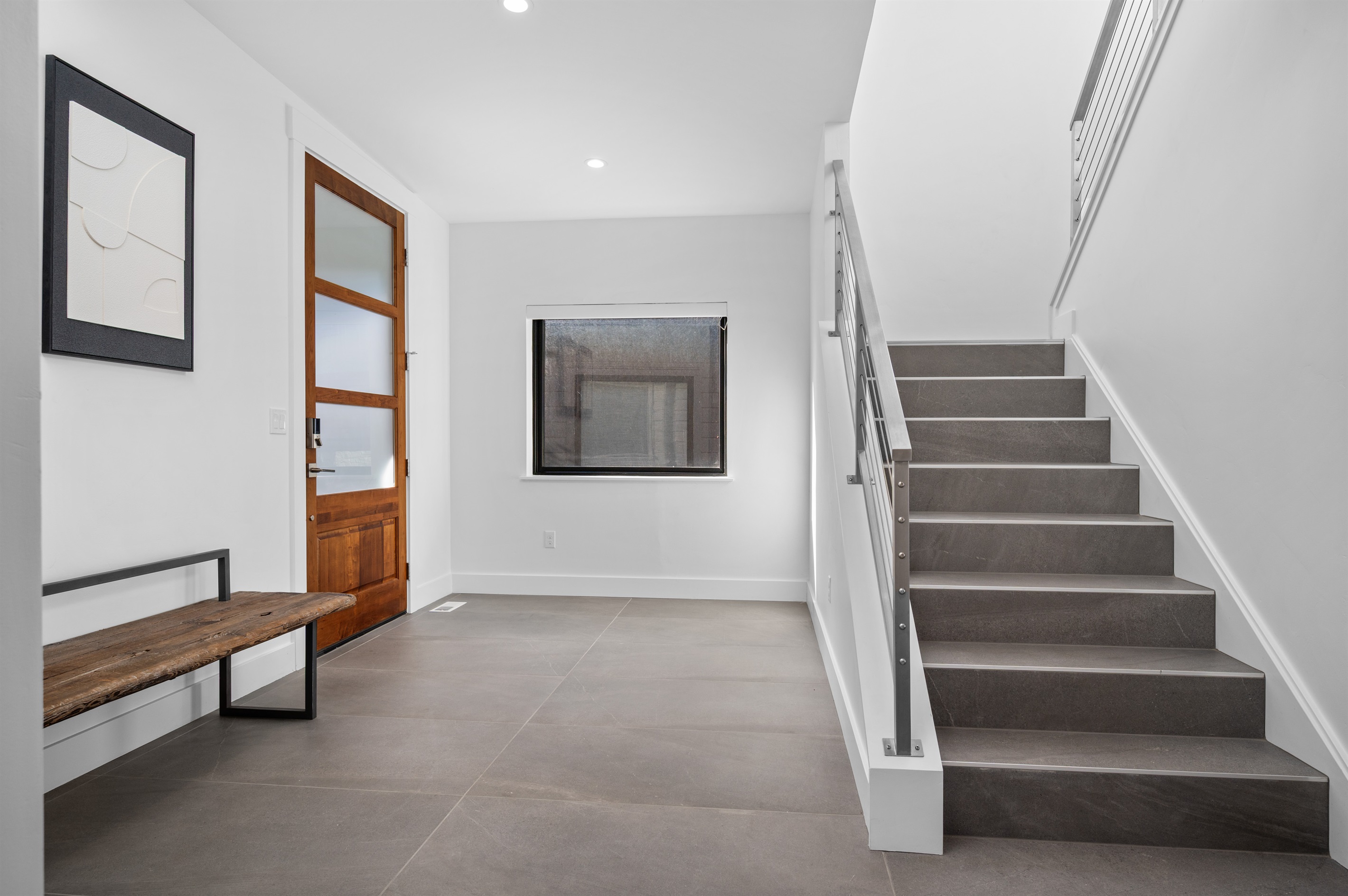Bright entryway with modern finishes and open staircase to the upper level.
