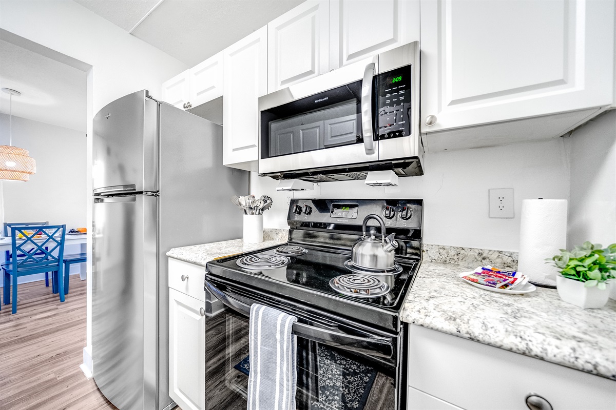 Fully stocked kitchen with glass top gas burner and oven and two door fridge