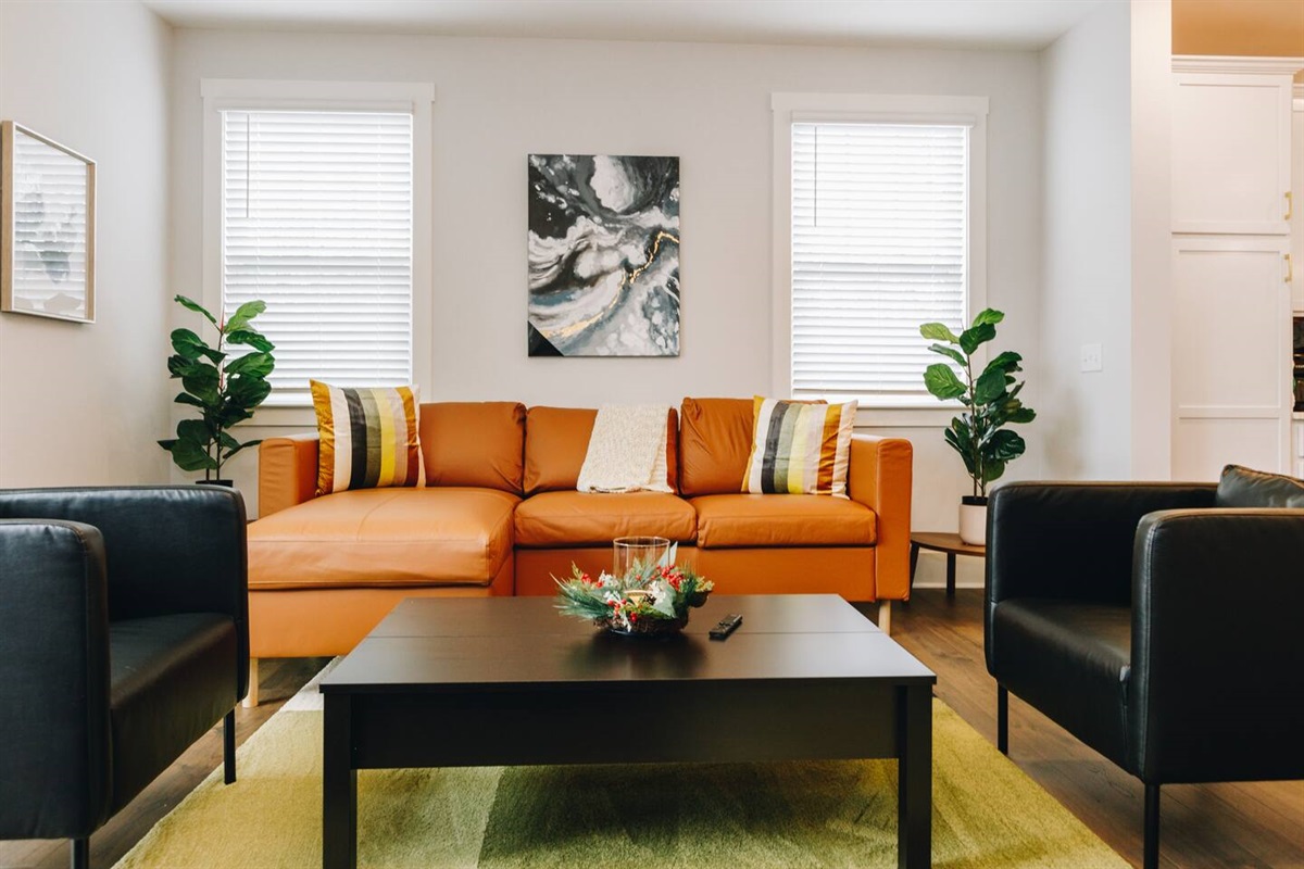Style and comfort come together in this trendy living room complete with leather sofa and extra seating around the large 65" smart TV.