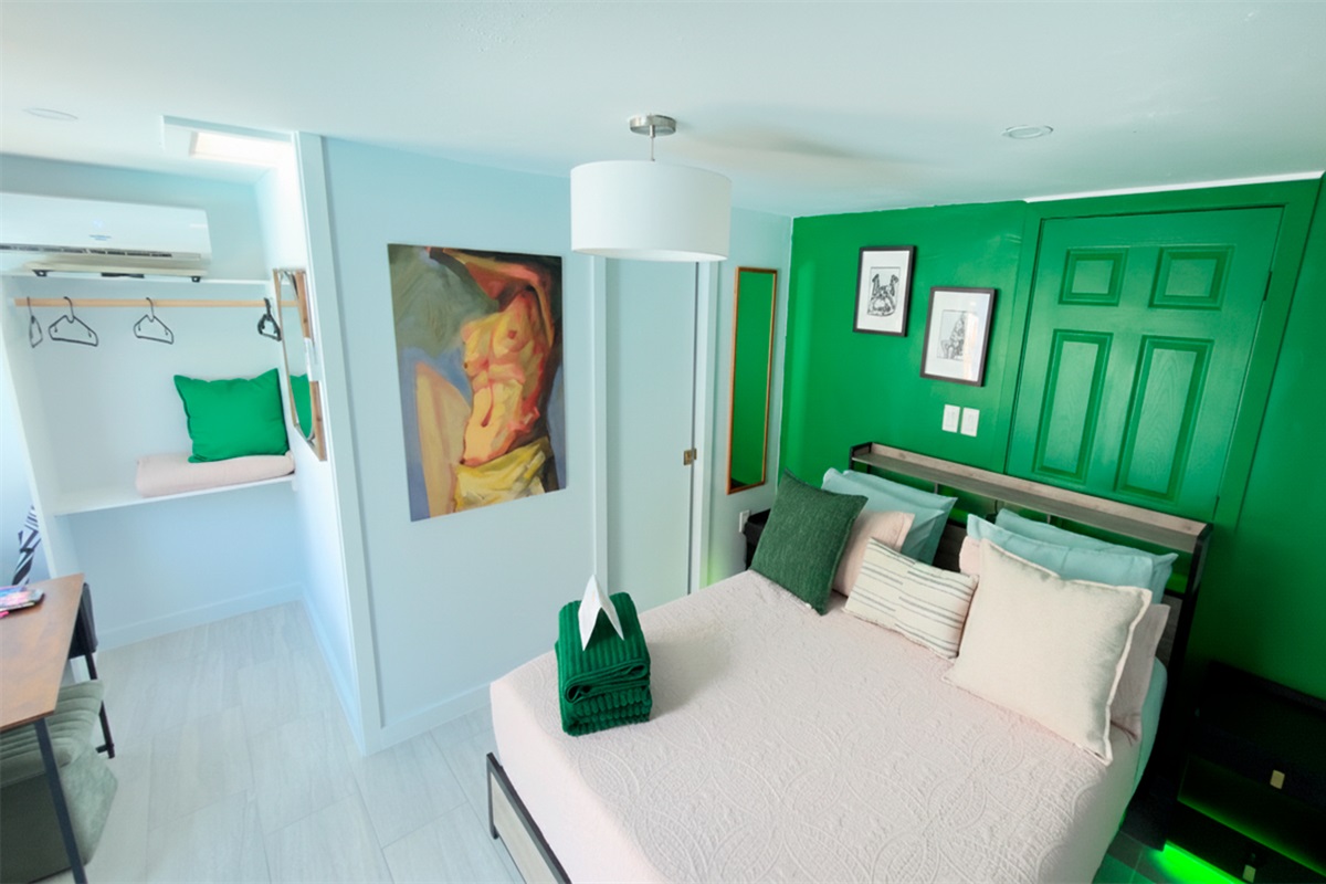 Bright and inviting bedroom in The Green Room, featuring a queen bed, fresh green accents, and a clean, modern design.