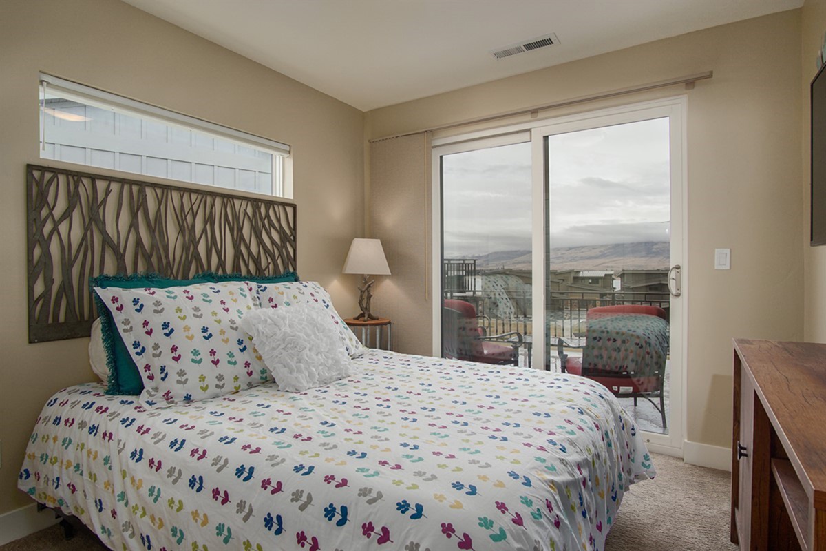 Bright bedroom with large window and scenic neighborhood and mountain views.