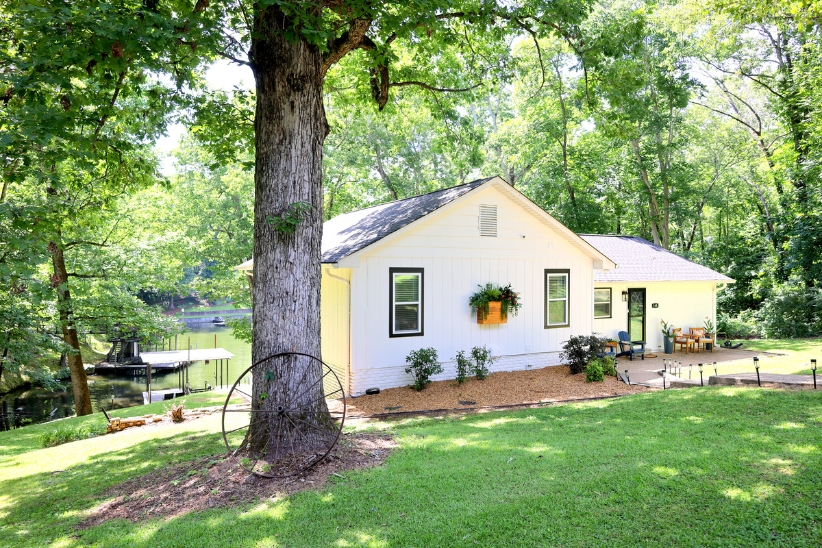 Side exterior view of the main home with lake access, wooded surroundings, and peaceful outdoor setting