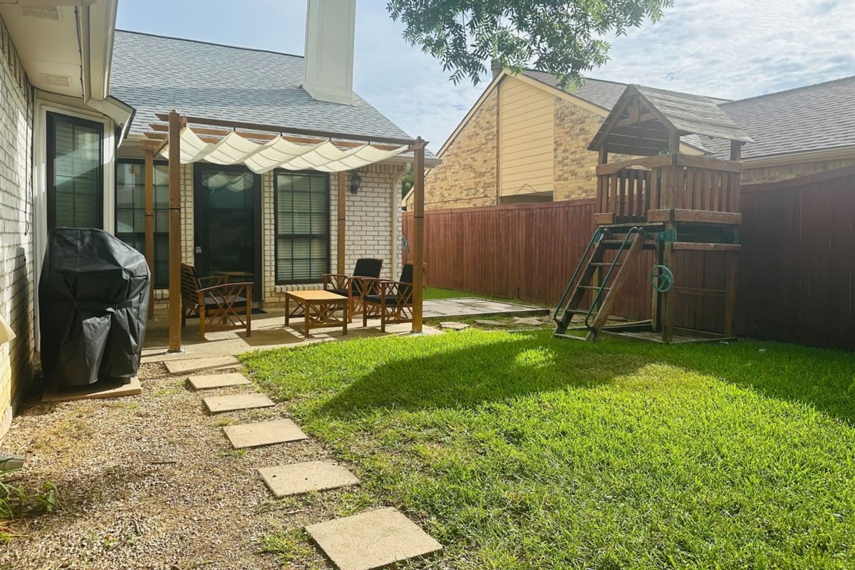 Private backyard with shaded seating and playset — ideal for family fun.