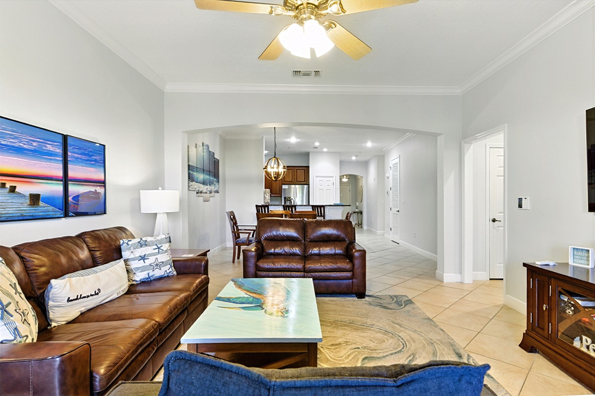 🛋️🌴 Bright, open, and beachy—this spacious living area is made for relaxing together with comfy leather seating, coastal décor, and an easy flow right into the dining space and kitchen. ✨📺
