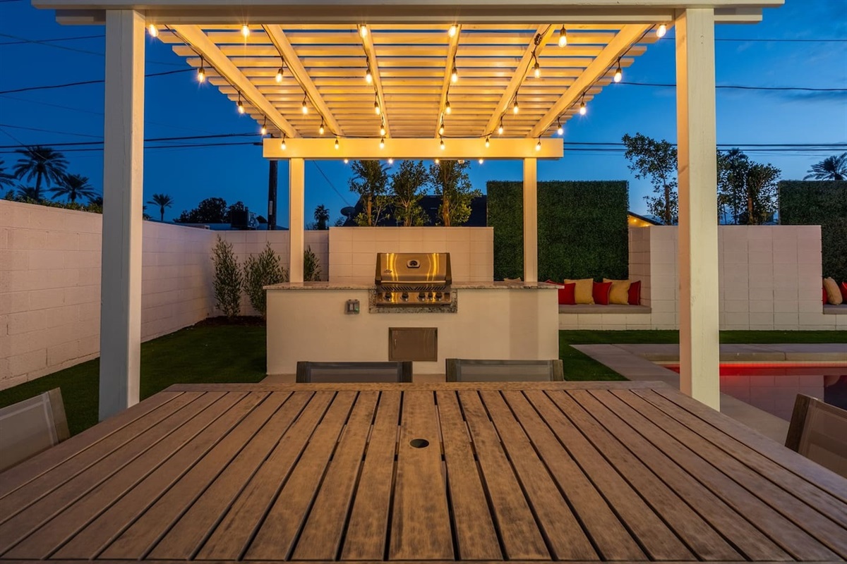 Enjoy alfresco dining under the pergola, equipped with a grill and preparation area, alongside a charming dining space for unforgettable meals with friends and family.