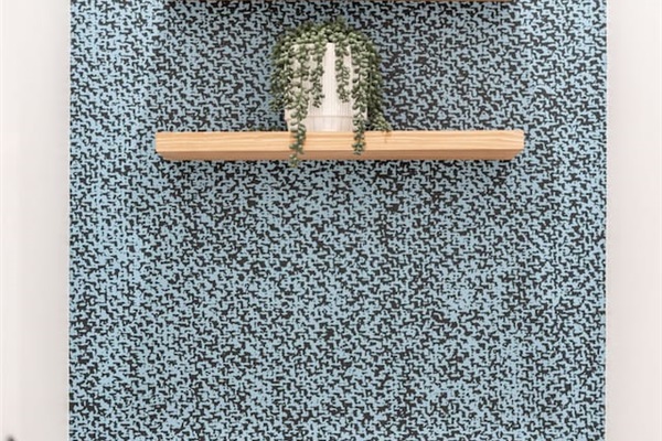 Stylish toilet nook with patterned accent wall and floating shelves.