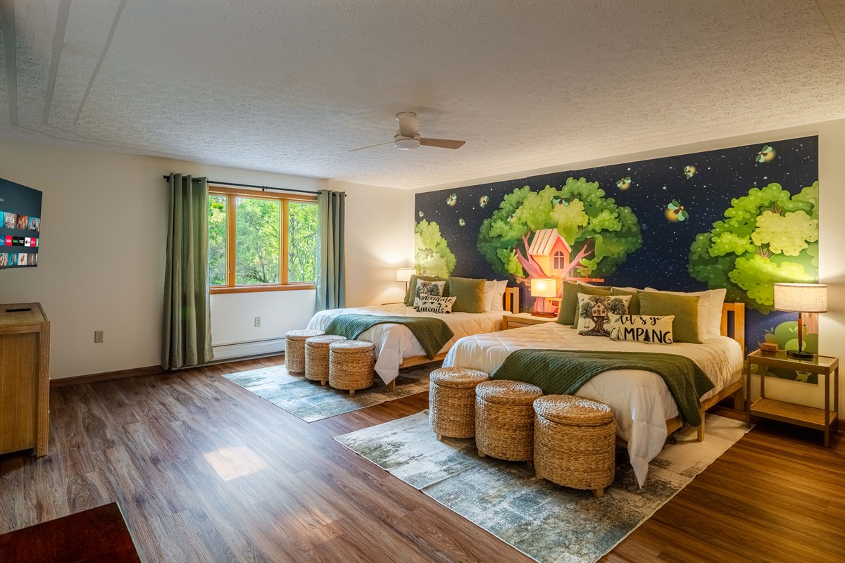 Whimsical treehouse murals and cozy double beds make this the ultimate kids’ camping room.