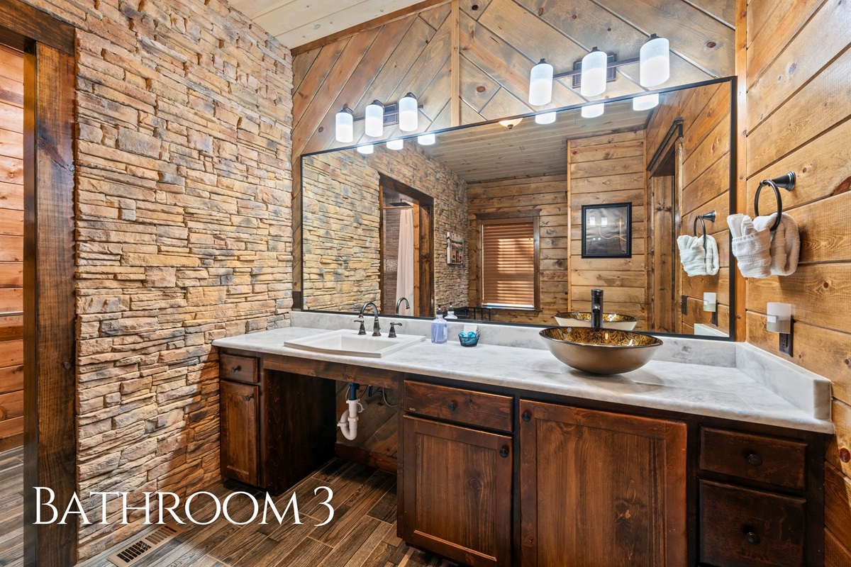 This well-appointed bathroom features dual sinks, generous counter space, and warm finishes, making it easy for multiple guests to get ready comfortably without feeling crowded.