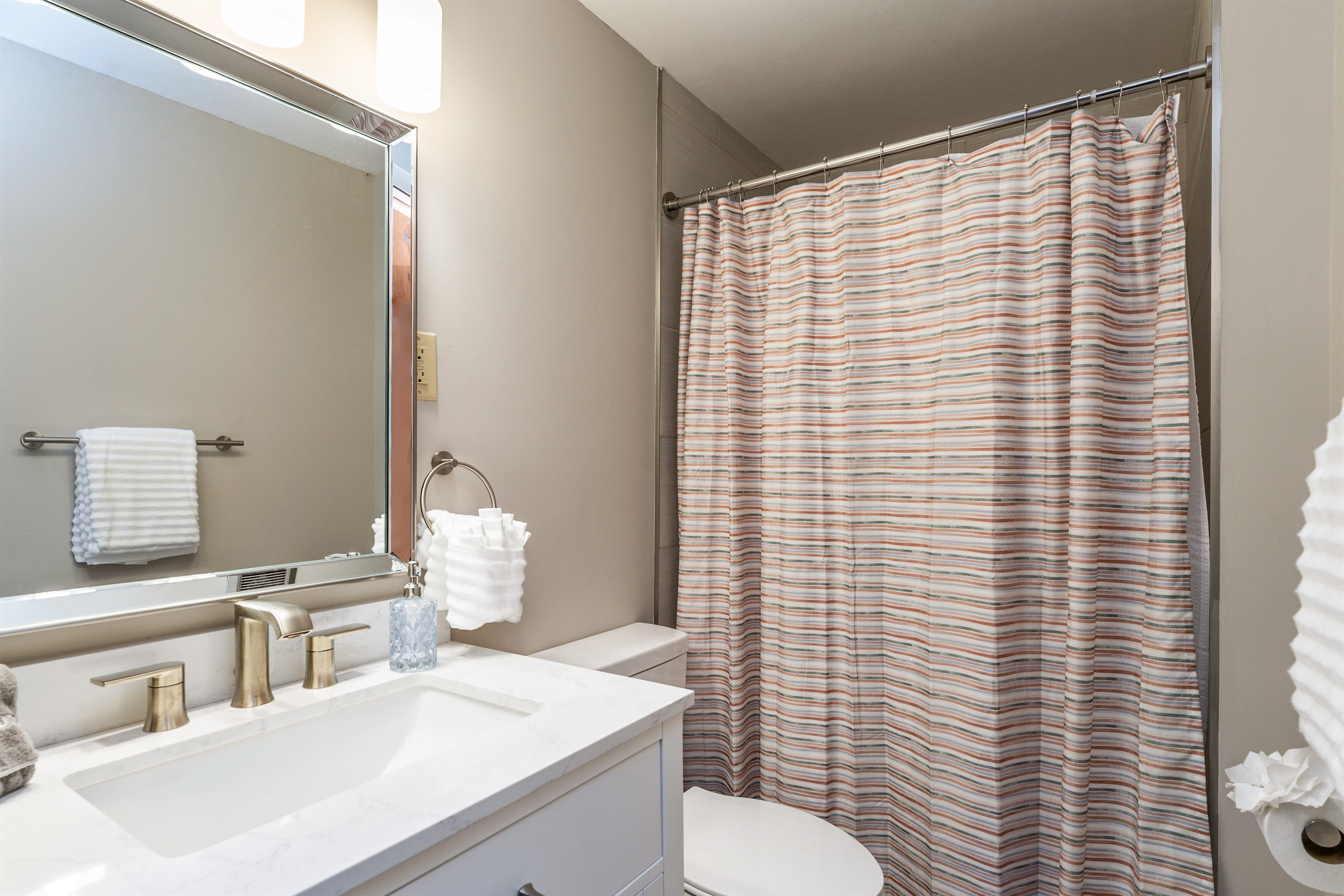 Fresh and modern bathroom with sleek fixtures, a marble vanity, and a cozy shower/tub combo—perfect for unwinding after a day of exploring.