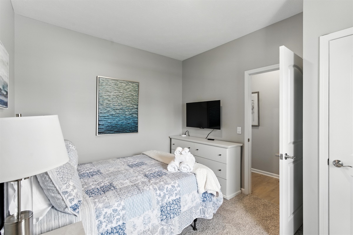 Cozy bedroom with queen bed nightstand and TV