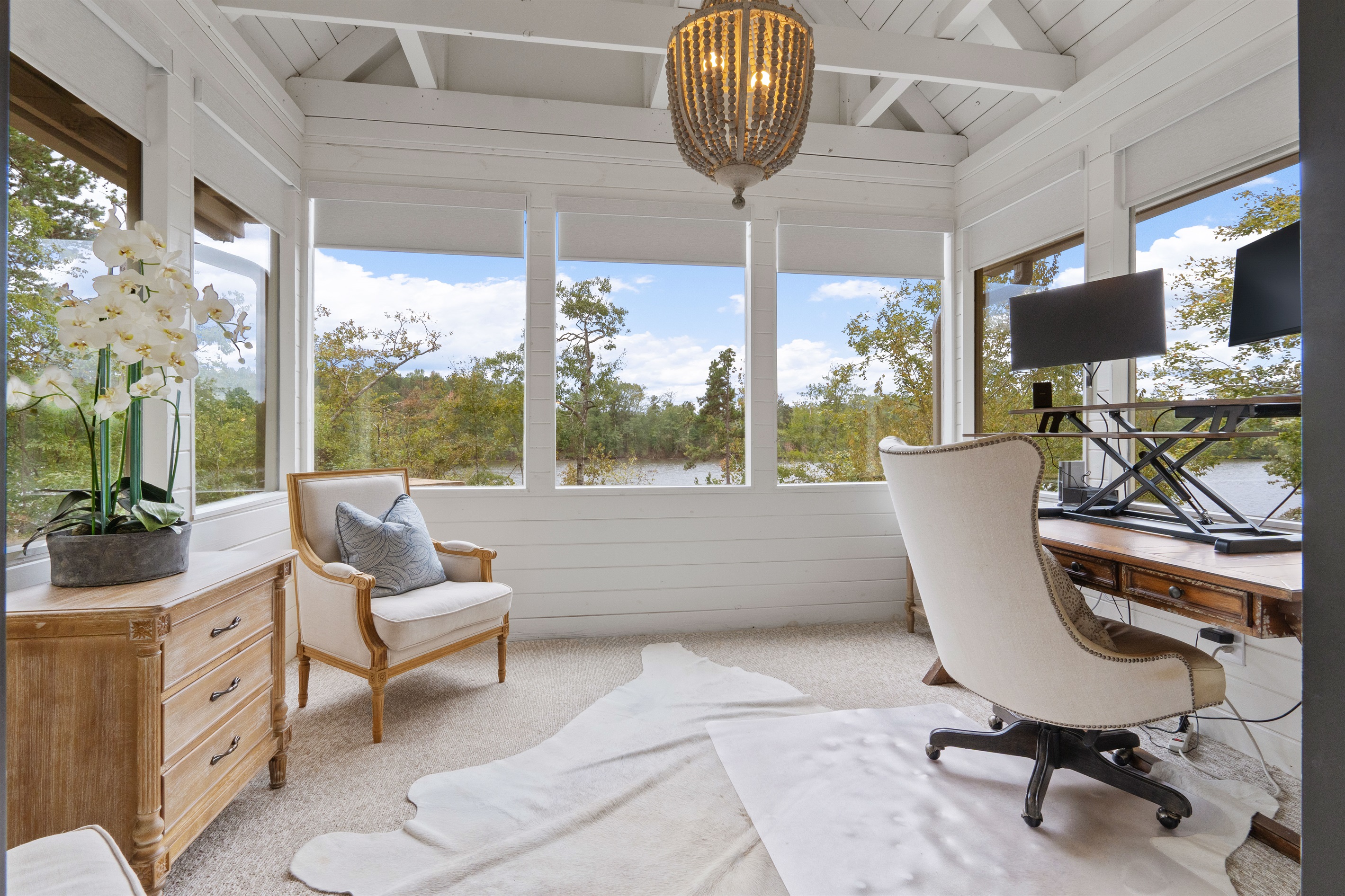 The office overlooks the lake with stunning 180° views and includes dual monitors, a stand-up desk, an ergonomic chair, and a printer—perfect for remote work or a productive retreat by the water.