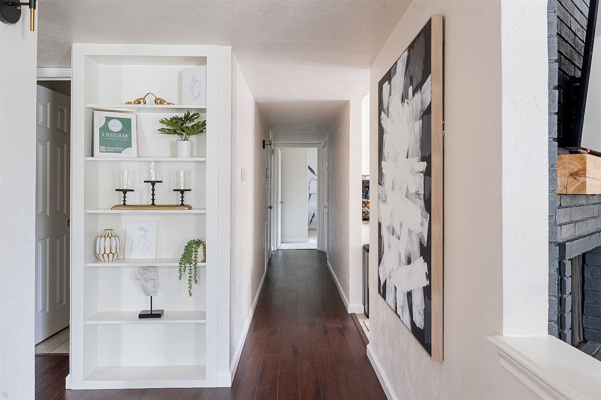 Walk down this artfully decorated corridor, featuring a stylish built-in shelf and modern artwork. The clean lines and decor enhance the inviting atmosphere.