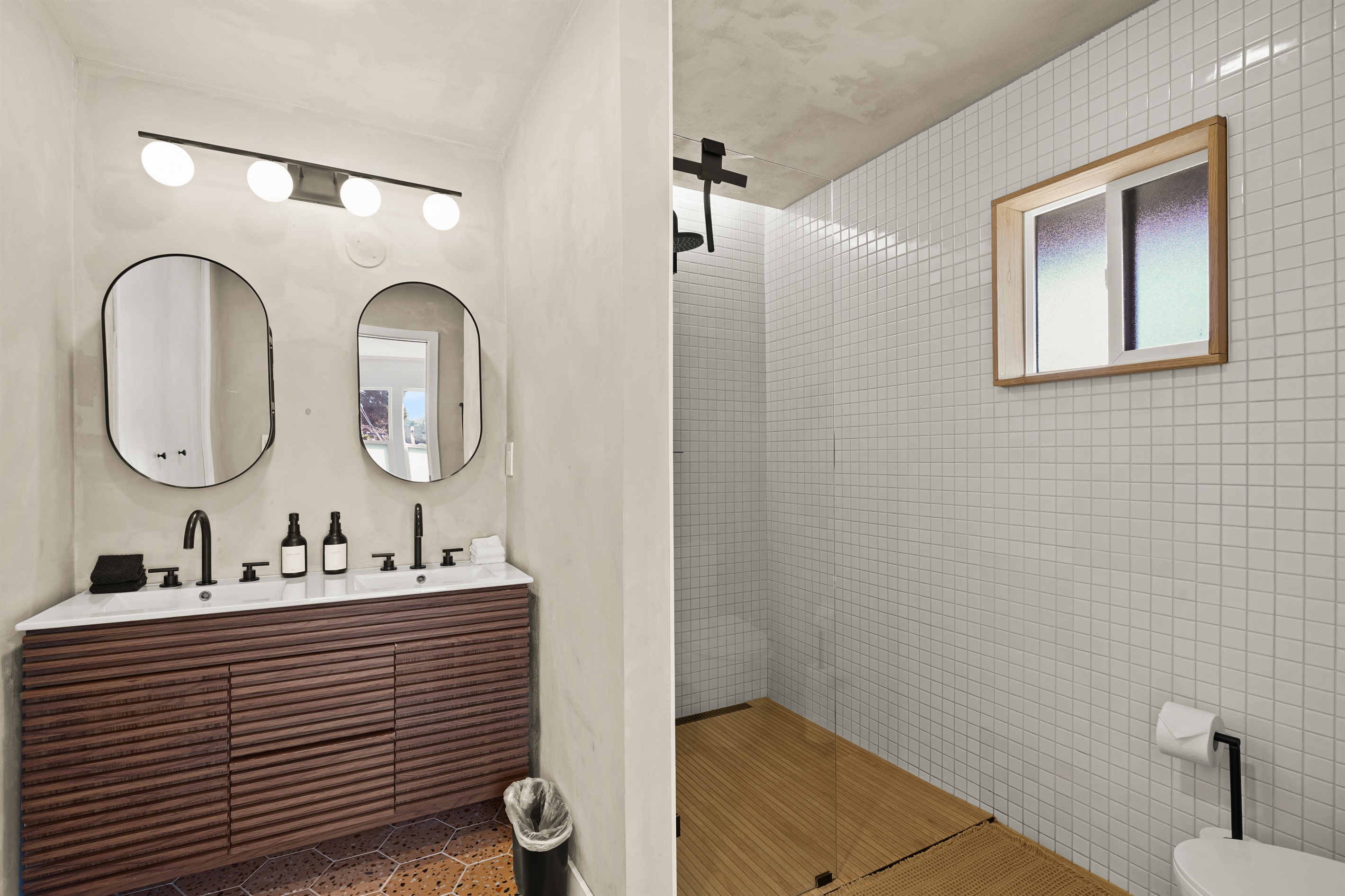 Bright and spacious bathroom featuring a double vanity and walk-in shower, offering plenty of room for guests to get ready comfortably.