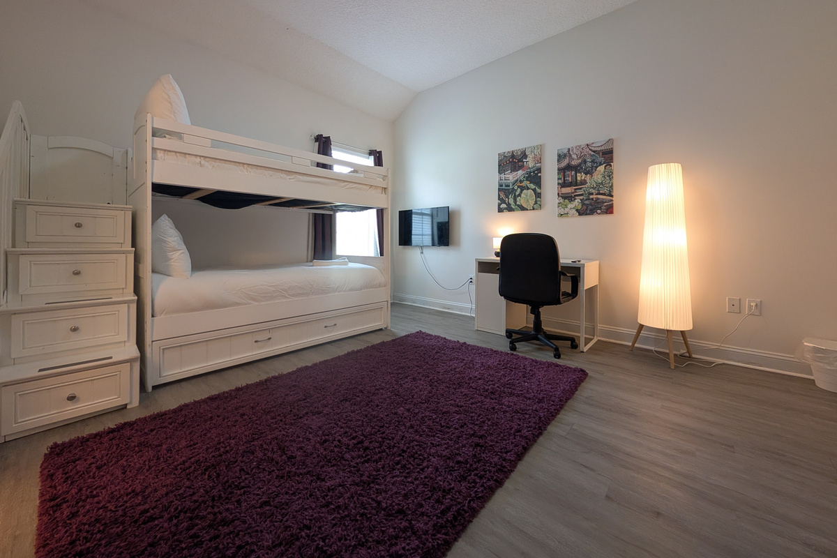 Roomy bunk bedroom with its own TV and workspace &mdash; a flexible setup for families and groups.