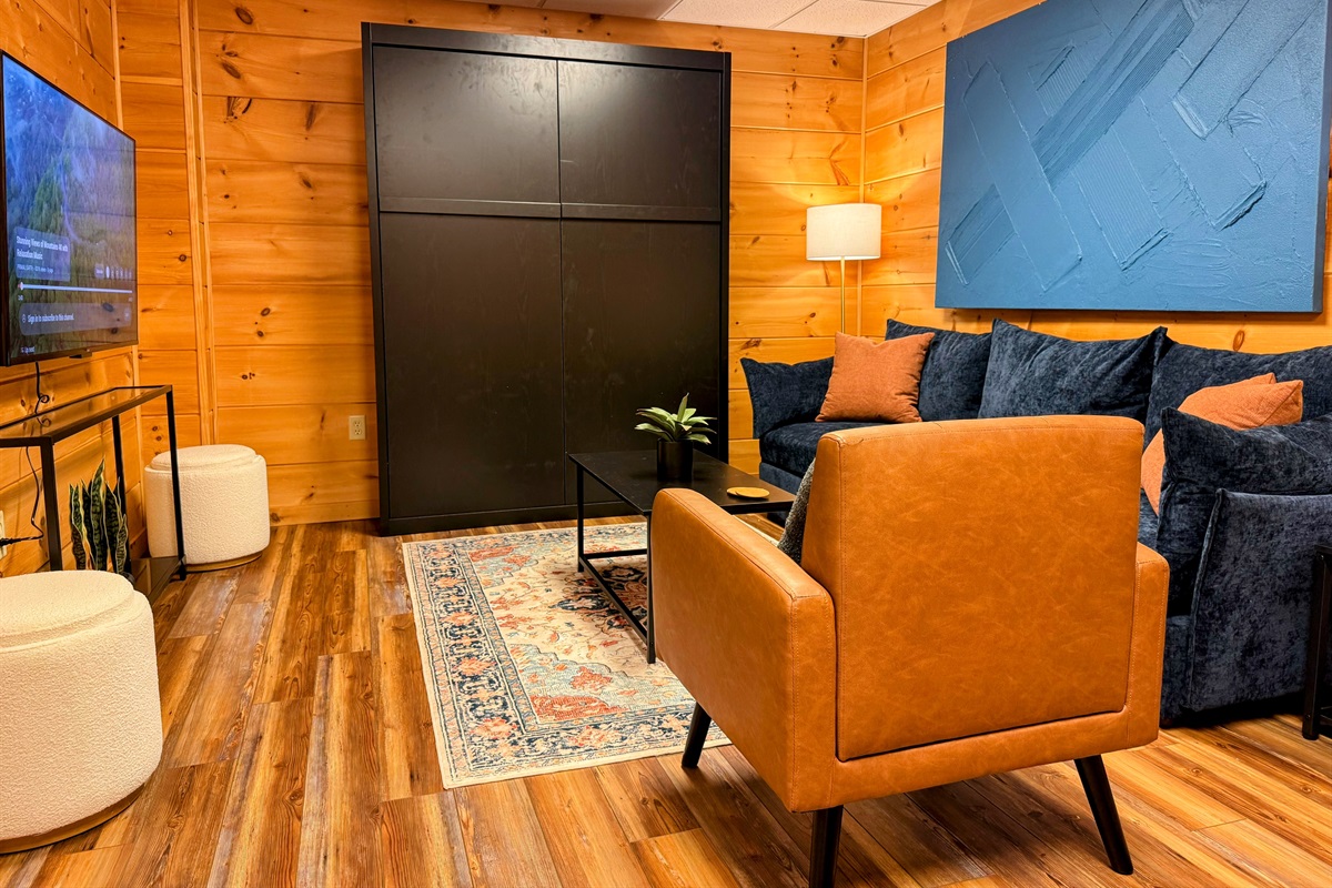 The lower level living area is thoughtfully designed, providing a comfortable space to relax and enjoy the Smart TV, with the added flexibility of a hidden Murphy bed for extra guests.