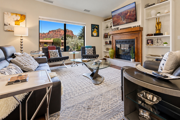A bright living room with comfortable seating, a fireplace, and Sedona red-rock scenery.