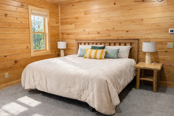 Spacious main-floor master bedroom featuring a king-sized bed, lake views, and in-room TV
