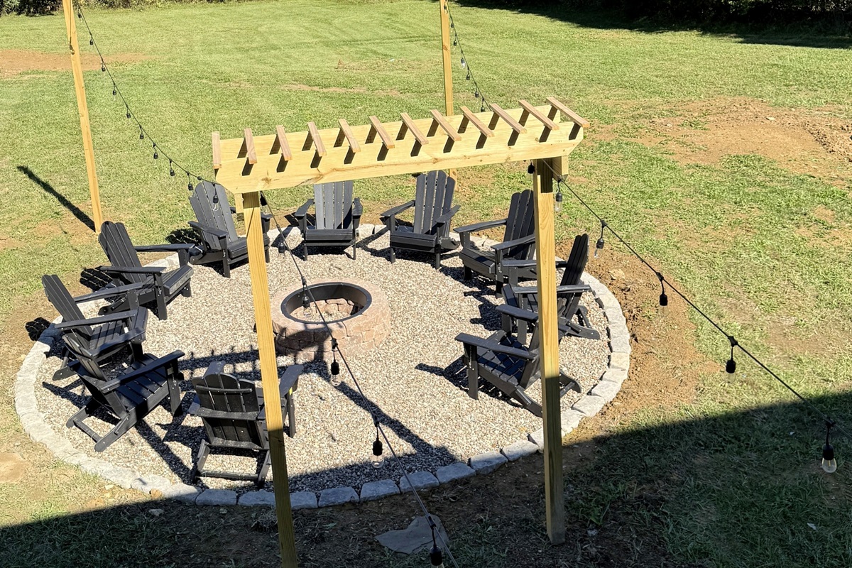 An inviting circle of craftsmanship and connection — the pergola and café lights set the stage for evenings that begin with stories and end in glowing embers.