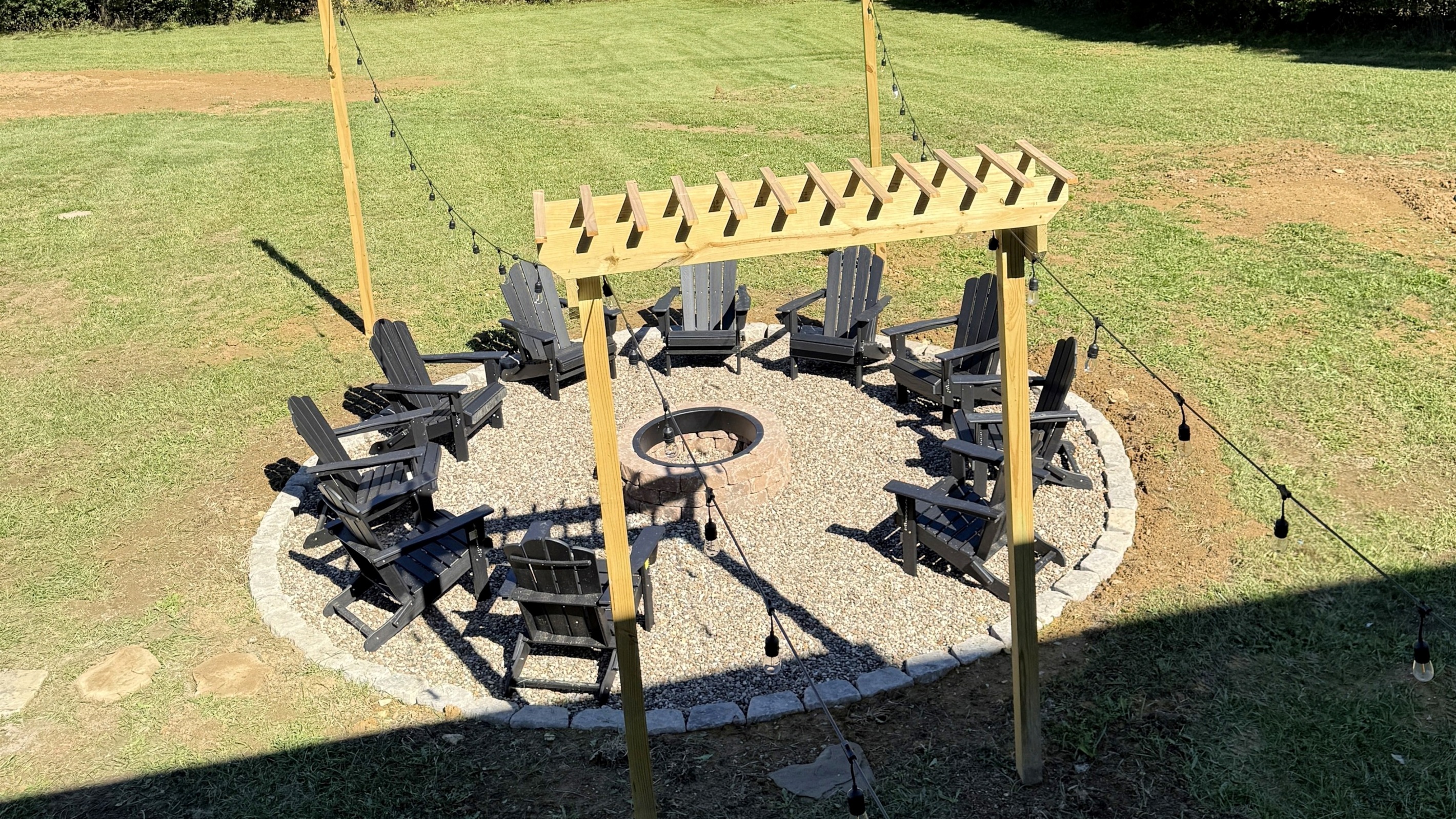 An inviting circle of craftsmanship and connection — the pergola and café lights set the stage for evenings that begin with stories and end in glowing embers.