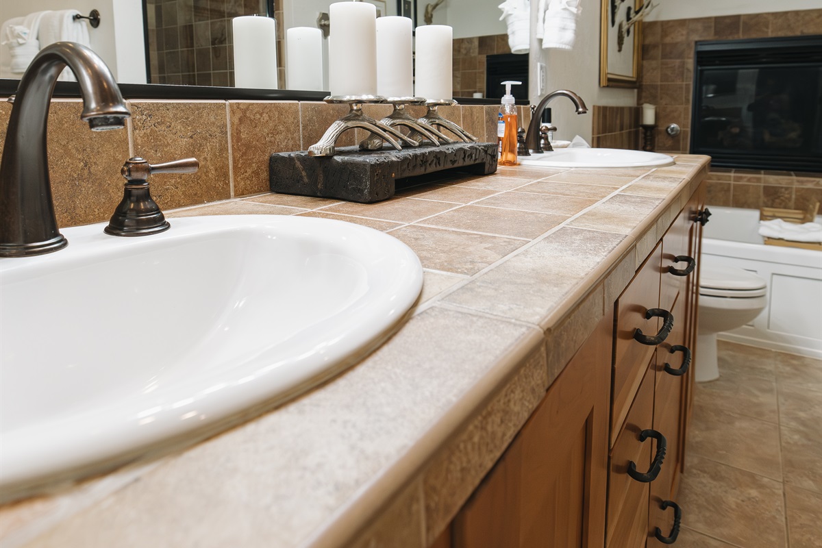 A warm, lodge-inspired bathroom with a double vanity, stone countertops, and soft ambient lighting. Thoughtfully styled with curated accents, plush towels, and premium fixtures, this spacious bathroom offers a calm, spa-like experience—perfect for slow mor