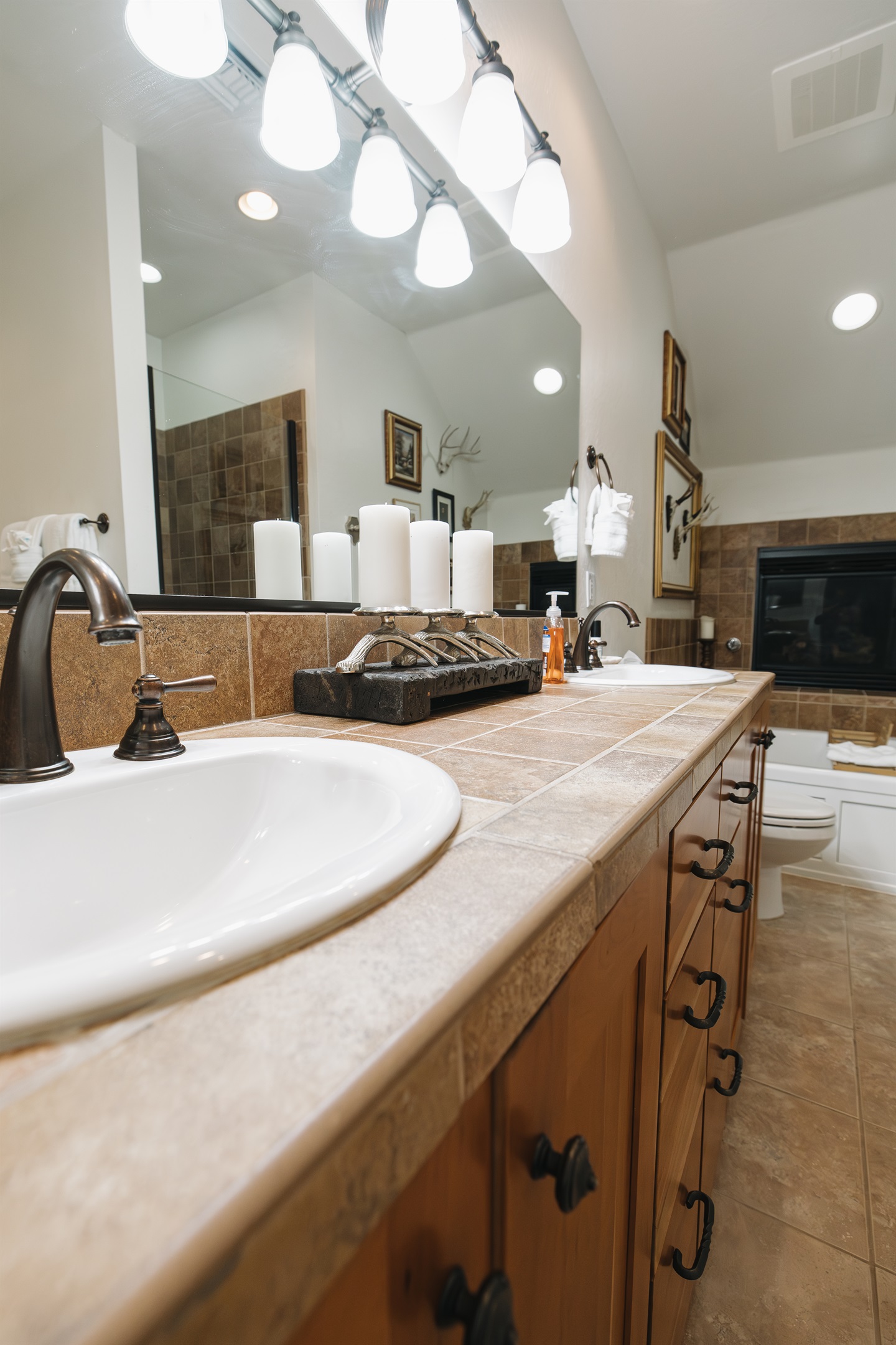 A warm, lodge-inspired bathroom with a double vanity, stone countertops, and soft ambient lighting. Thoughtfully styled with curated accents, plush towels, and premium fixtures, this spacious bathroom offers a calm, spa-like experience—perfect for slow mor