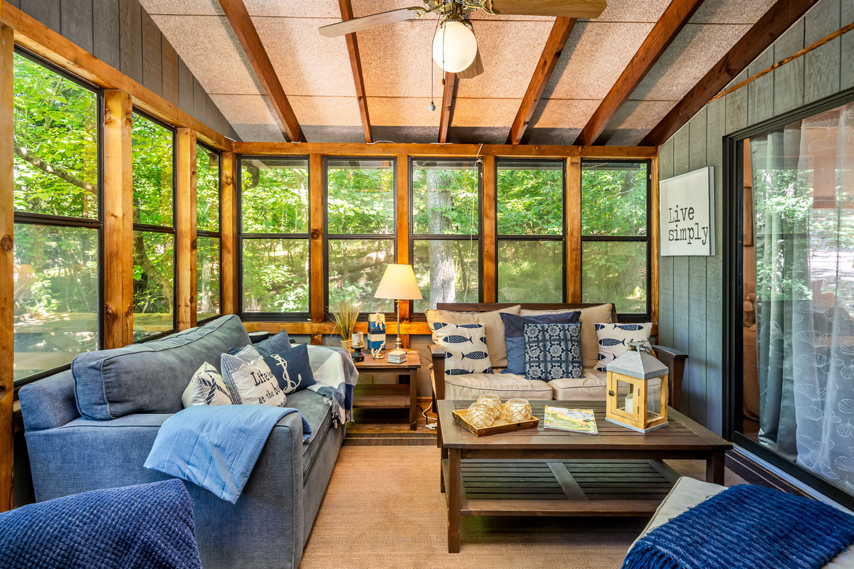 Step out of the master bedroom into the screened sunroom — wicker chairs, morning coffee, and nothing but trees outside.