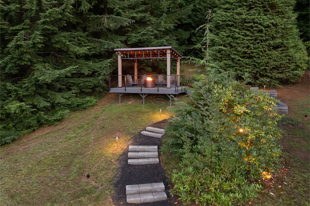 A cozy gazebo with Adirondack chairs and a glowing firepit—perfect for unwinding with a view