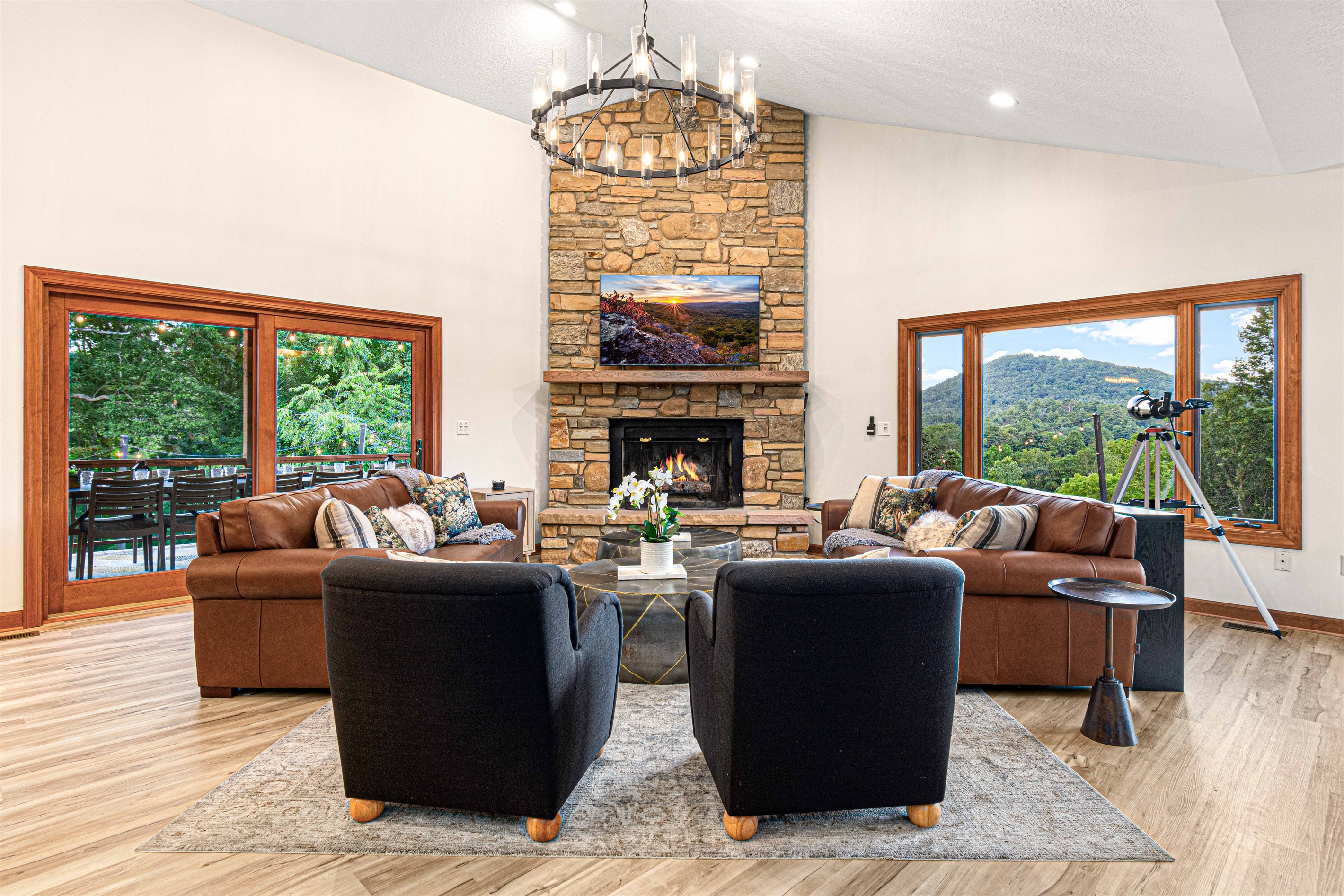 Gather in the main living room around the stone fireplace—plush seating, a dramatic chandelier, and panoramic mountain views set the scene for connection and comfort. 🔥⛰️✨