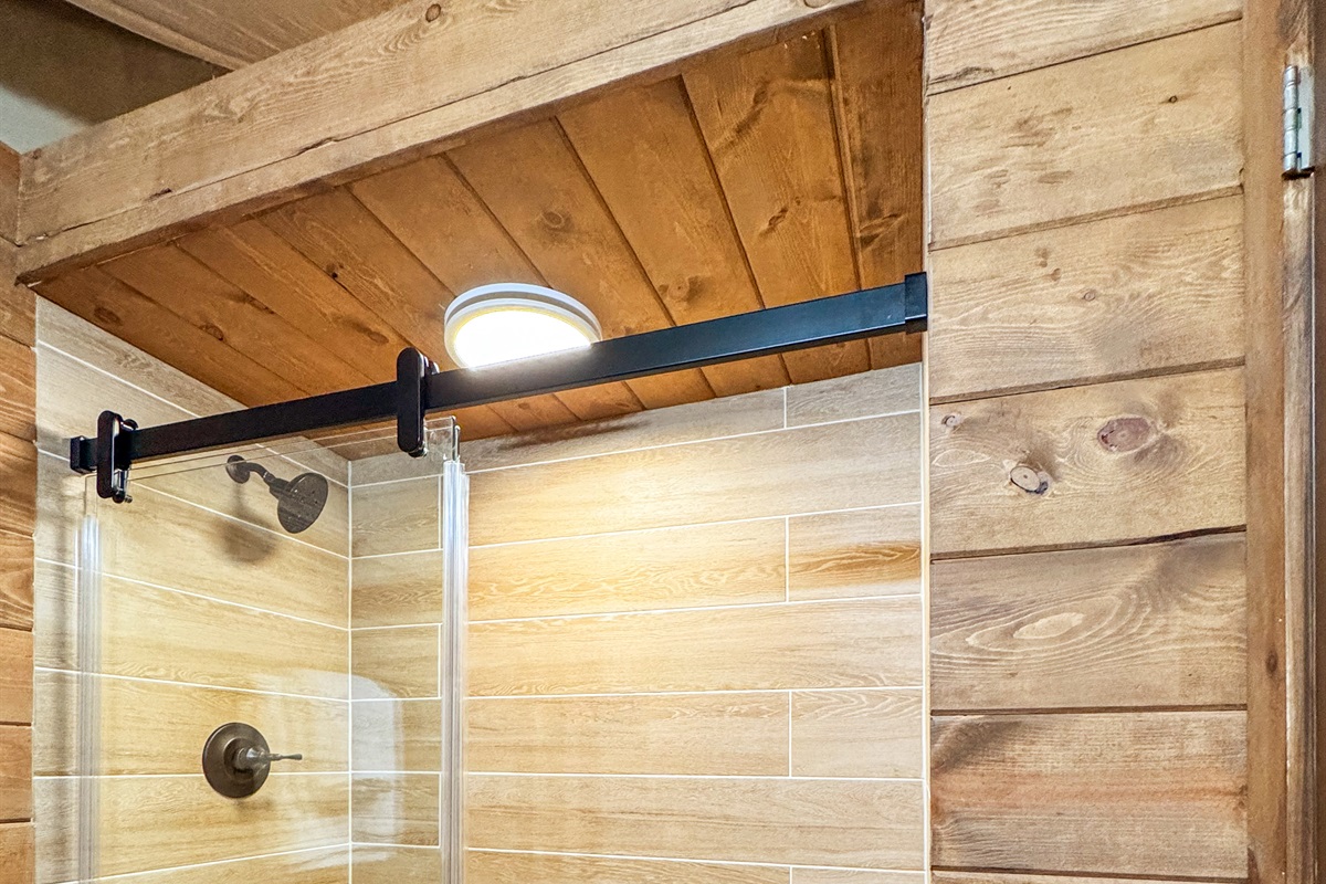 Enjoy a sleek glass shower with rustic wooden accents and stylish fixtures!